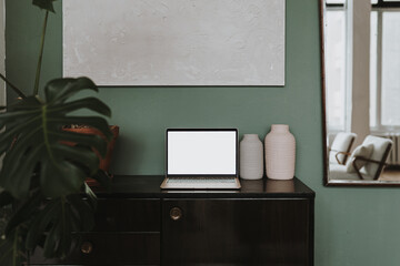 Wall Mural - Laptop computer with blank screen, clay pots, monstera leaf on console. Aesthetic template with mockup copy space. Online store, blog, social media, website branding. Online shopping concept