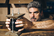 Male Artisan Adjusting Cup In Wooden Press