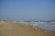 Brandung mit weißem Schaum am Strand der Nordsee mit Blick Richtung Zeebrügge bei blauem Himmel und Sonnenschein in Knokke-Heist bei Brügge in Westflandern in Belgien