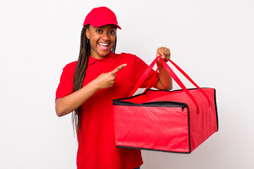 Wall Mural - young adult black woman looking excited and surprised pointing to the side. pizza delivery concept