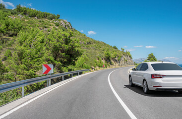 Wall Mural - A white car drives along a beautiful road on a sunny summer day.