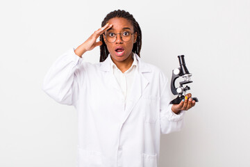 Wall Mural - young adult black woman looking happy, astonished and surprised. sciencist with microscope