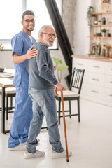 Wall Mural - Healthcare worker helping a man to walk with a cane