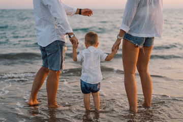 Wall Mural - Happy family having fun playing beach in summer vacation on the beach. Happy family and vacations concept. Seascape at sunset with beautiful sky. Family on the beach.