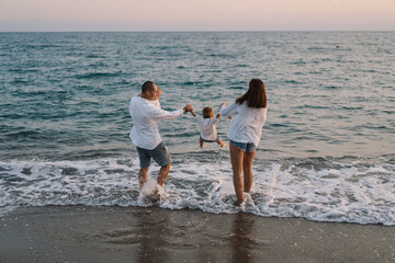 Happy family having fun playing beach in summer vacation on the beach. Happy family and vacations concept. Seascape at sunset with beautiful sky. Family on the beach.