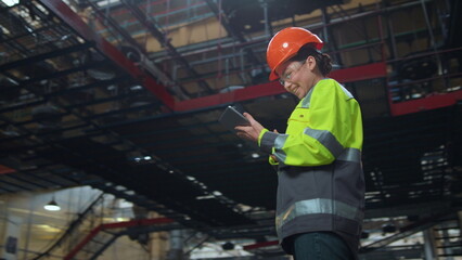 Wall Mural - Woman supervisor holding tablet computer at huge modern manufacturing storage.