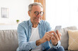 © Prostock-studio - Portrait of mature man using smartphone sitting on couch