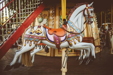 Retro Carousel White, Black Horse. Old Wooden Horse Carousel. Carousel! Horses On Vintage, Retro Carnival Cheerful Walk. CloseUp Of Colorful Carousel With Horses. Vintage Photo Processing