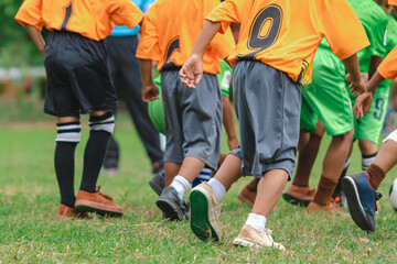 Wall Mural - Football soccer children training class. Kindergarten school kids playing football in a field. Group of boys running and kicking soccer on sports grass pitch. Children in sportswear on football match.