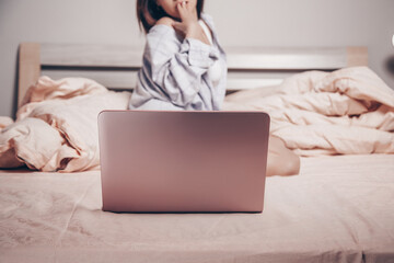 Wall Mural - focus on the laptop. at the laptop, a young Asian girl enjoys and shows her charms. low depth of focus,selective focus