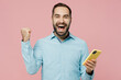 © ViDi Studio - Young happy overjoyed cool man 20s in classic blue shirt hold in hand use mobile cell phone do winner gesture isolated on plain pastel light pink background studio portrait People lifestyle concept