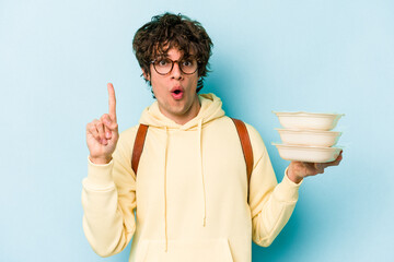 Young caucasian student man holding a tupperware isolated on blue background having some great idea, concept of creativity.