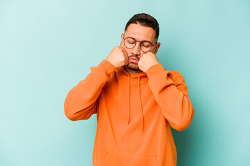 Wall Mural - Young hispanic man isolated on blue background whining and crying disconsolately.