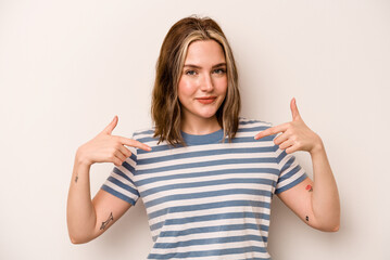 Wall Mural - Young caucasian woman isolated on white background person pointing by hand to a shirt copy space, proud and confident