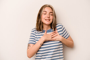 Wall Mural - Young caucasian woman isolated on white background has friendly expression, pressing palm to chest. Love concept.