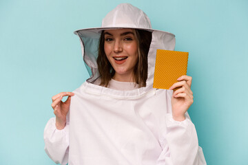 Wall Mural - Young caucasian beekeeper woman isolated on blue background