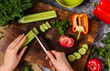 © irocket - Cutting fresh cucumber on wooden cutting board with japanese knife. Making vegetable salad.