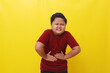 © ArvStd - Asian boy standing holding stomach feeling pain. Healthcare concept. Isolated on yellow background