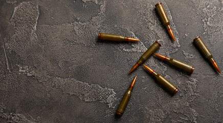 Bullets on black textured marble. Bullets of a kolashnikov assault rifle close-up with space for text. Cartridges for a rifle and a carbine on a wooden background. Military concept. copy space