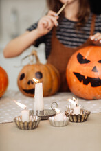 Child Girl Lights A Candle For Halloween. Little Girl In Witch Costume With Carving Pumpkin With A Face Made By Child. Happy Family Preparing For Halloween. Selective Focus