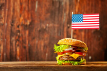 Close-up Home Made Beef Burger With American Flag On The Top On Wooden Table Over Old Wooden Background.