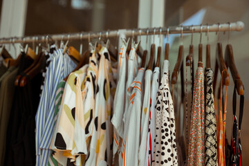 Wall Mural - Hangers with different female clothes presenting at the retail store.