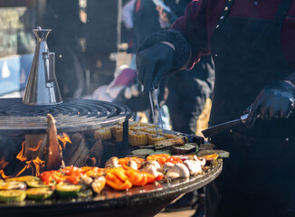 The cook cooks vegetables on the grill on the fire. Fish Festival in Svetlogorsk Raushen, Kalinigrad region, Russia, near the Baltic sea.