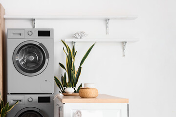 Modern washing machines near light wall in kitchen