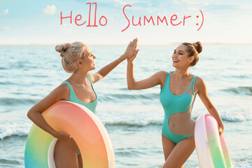 Sticker - Beautiful young women with inflatable rings giving each other high-five on sea beach. Hello, summer