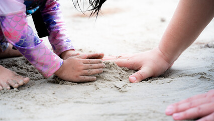 Wall Mural - Family travels to the sea during summer holidays. Close Up father and daughter hands are building sand castle on beach. Empty space for entering text.