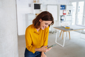 Wall Mural - Young business woman looking at her cell phone laughing