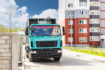 Fototapete - A garbage truck picks up garbage in a residential area. Loading mussar in containers into the car. Separate collection and disposal of garbage. Garbage collection vehicle.