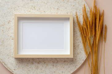 Wall Mural - blank photo frame with pampas grass on marble stand at peach table