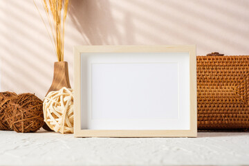 Wall Mural - blank photo frame with wicker stuff on cement table and peach wall