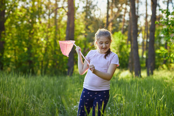 Wall Mural - A girl catches butterflies with a pink juice on a summer day