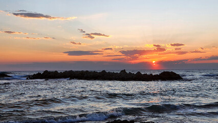 Wall Mural - colorful sunset with large sun under the sea waves.