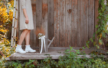 Women's Feet In Dress And White Shoes, Fashion Background Wooden Planks Gardener Iron Watering Can, Free Space For Text