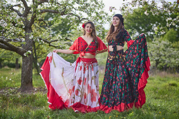 two dancers in traditional gypsy dresses dance in nature on a spring day