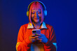 canvas print picture Asian girl in headphones smiling and using mobile phone