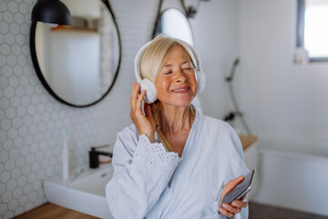 Poster - Beautiful senior woman in bathrobe listening to music in bathroom, relax and wellness concept.