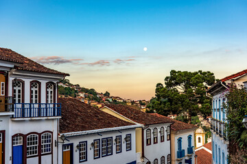 Wall Mural - Old colonial style houses with their balconies in the traditional historic town of Ouro Preto during sunset with the moon in the background