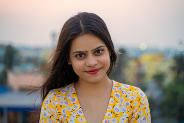 A close-up headshot portrait of a young, beautiful, confident and attractive Indian Asian woman in the outdoor. Happy and natural smiling teenage girl looking at the camera