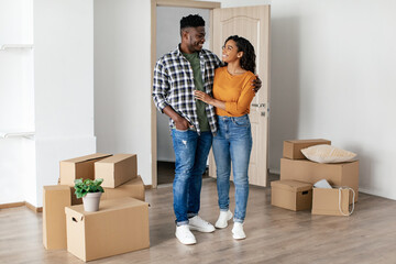 Wall Mural - Cheerful African Couple Embracing Standing After Relocation In New Home