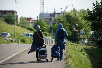 Portrait on back view of muslim women walking in the street with market trolleys