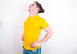 © Roquillo - Young caucasian man wearing yellow t-shirt over white background got back pain