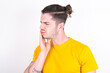 © Roquillo - Young caucasian man wearing yellow t-shirt over white background with toothache