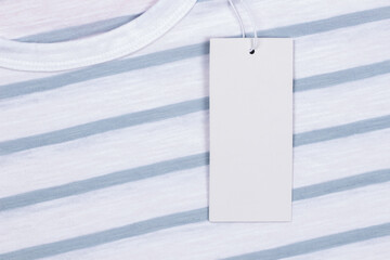 Canvas Print - Blank white rectangular label tag on white striped t-shirt clothes background. Price tag tabel mock up with copy space