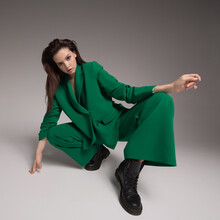 Fashion Portrait Of A Charming Girl Dressed In A Green Suit. Gray Background.
