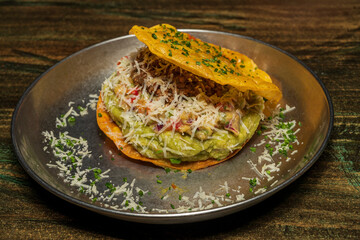 Crispy puff pastry taco with guacamole and cheese stuffed with avocado and various vegetables on a metal plate