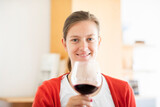Fototapeta Na drzwi - Junge blonde Frau zu Hause entspannt mit einem Glas Rotwein au fem Sofa